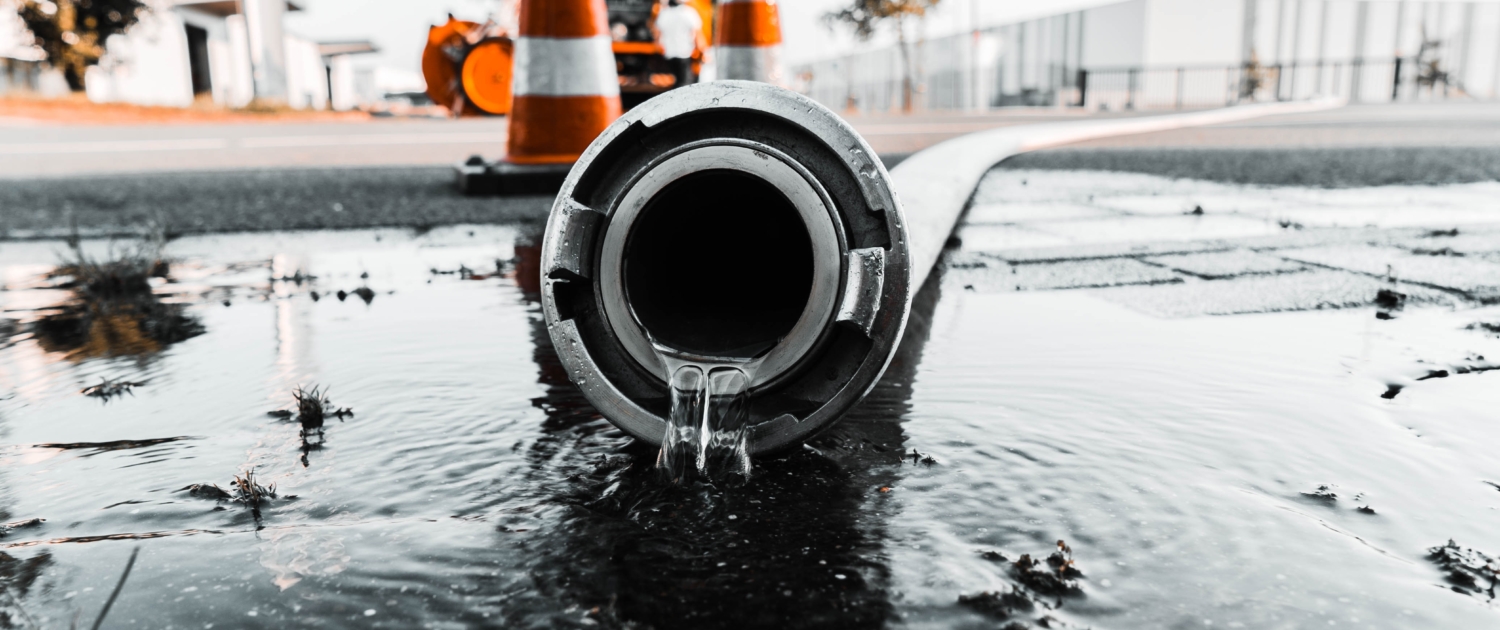 Selective closeup shot of a gray pipe with water coming out its hole